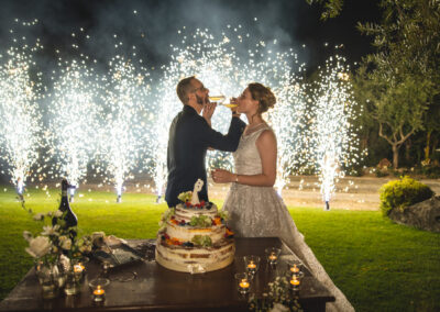 lo sposo e la sposa brindano davanti alla torta nuziale con uno sfondo di fontane di fuoco